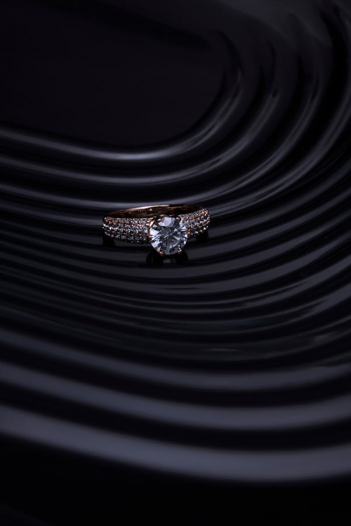 Close-up of a diamond ring with a dark, wavy background creating a luxurious and elegant atmosphere.